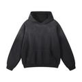 A washed black pullover hoodie with a small printed graphic on the left chest, displayed against a solid white background.