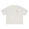 Front of a boxy heavyweight tee in Oat Gray with a small sitting-cat epicycle drawing on the left chest.